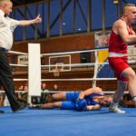 Borac iz plavog kuta leži na podu nokautiran, dok protivnik iz crvenog kuta slavi