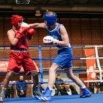 Boksac udara svog protivnika u glavu, sa publikom u pozadini