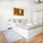 Krevet u velikoj sobi za slikom iznad zaglavlja i sivim plahatama na krevetu