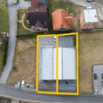 Pogled dronom odozgo na skladište, s praznim poljem s obe strane