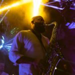 Saksofonist na pozornici iz donje perspektive sa zlatnim svijetlom iznad njega