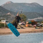 Kiter u skoku ispred plaže sa plavom daskom nitron