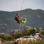 Profesionalni kite surfer drži dasku rukom dok leti u zraku