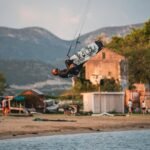 Kiter radi backflip u zraku ispred pješčane plaže