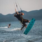 Kiter u zraku sa morem ispod njega, brdom ispred i sve je u blijedoj plavoj nijansi