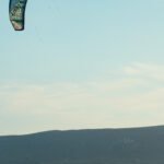 Minimalisticka perspektiva kite surfera gdje je padobran smješten u gornji lijevi kraj, a surfer u donji desni