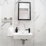 WC s plocicama mramornog uzorka, bijelim umiovaonikom i ogledalom s crnim okvirom