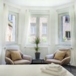 Dvije svijetlo smede fotelje u spavacoj sobi ispod velikih prozora