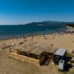 Fotografija drvenog beach bara na pješčanoj plaži, smještenog uz obalu i okruženog morskim pejzažom